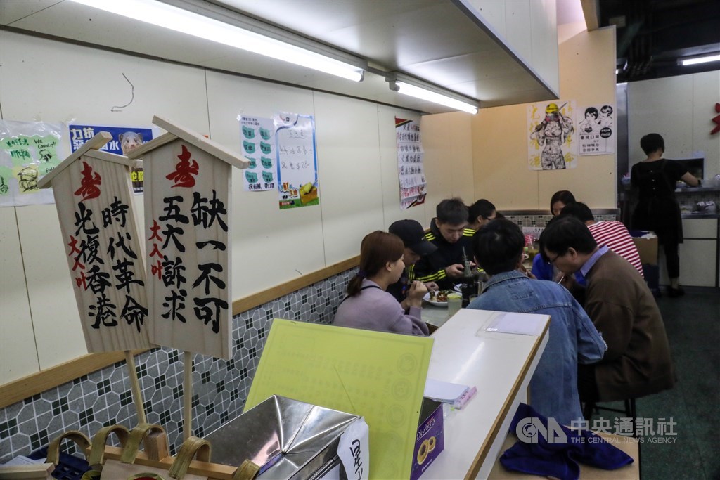 光榮冰室荃灣店大方展示寫著「五大訴求缺一不可」「光復香港 時代革命」的立牌。用餐時間店裡經常滿座，門外還有人排隊。中央社記者吳家昇攝　108年11月21日