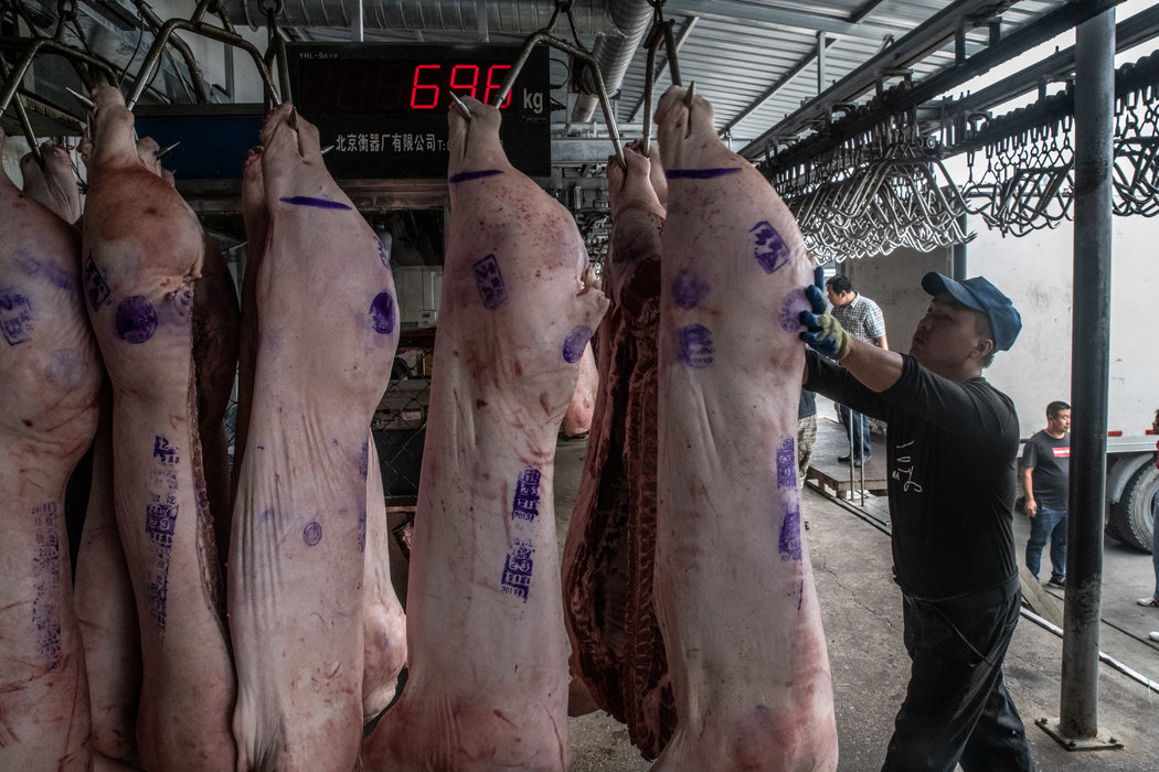 北京郊區的一個國家豬肉儲備倉庫，工人正在從卡車上卸貨。