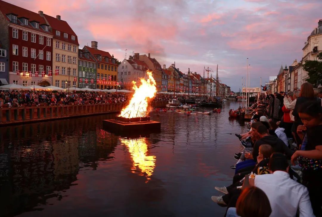 ▲当地时间2021年6月23日晚，人们在丹麦哥本哈根新港观看庆祝仲夏节的篝火晚会。图/新华社