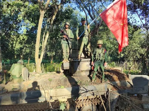 ◆2023年10月27日，果敢同盟军的士兵在占领掸邦北部缅军哨所后，与民族民主联盟旗帜合影。